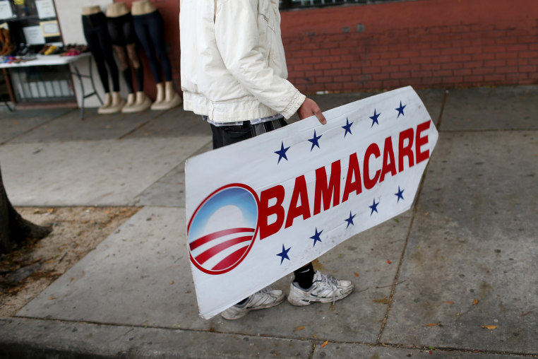 Image: Pedro Rojas holds a sign directing people to an insurance company where they can sign up for the Affordable Care Act, also known as Obamacare
