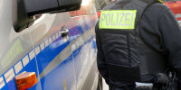 A police officer stands next to a police car