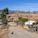A village is seen outside with a dog laying in the street and a mountainscape in the background
