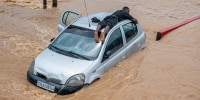 A man lies on top of a car stuck in floodwaters in the Ndjili district of Kinshasa, Democratic Republic of Congo, on April 6, 2025.