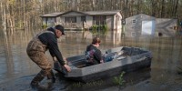Dusty Baggett uses a boat to push his wife Rachel through floodwater to their home on April 7, 2025 in Paducah, Ky.