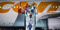 People walk down the stairs of a plane outside